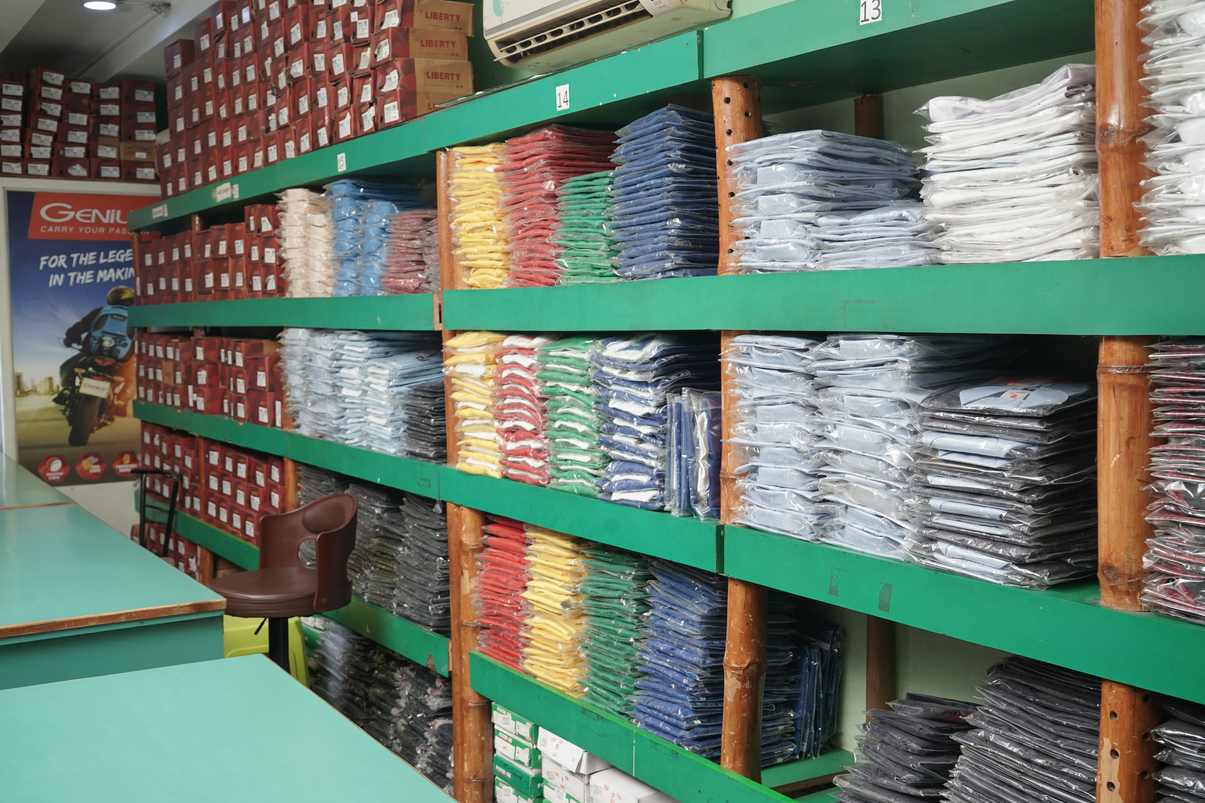 Trousers folded on the green shelving at Mohali, shoe boxes above
