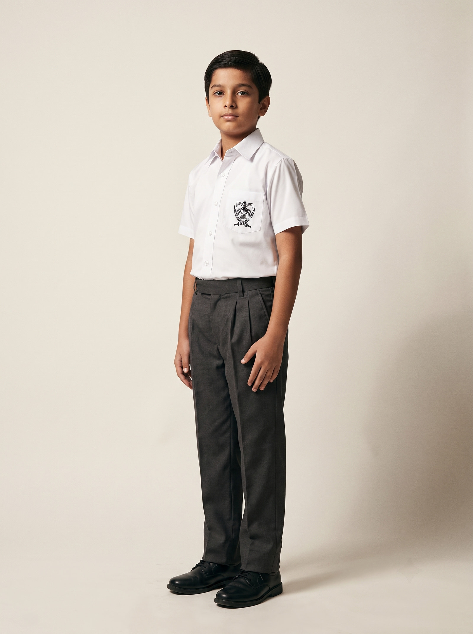 White cotton-and-polyester shirting carrying the school crest, over charcoal grey trousers.